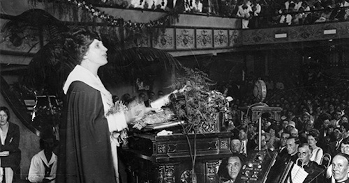 Aimee Semple McPherson pregando no púlpito diante da congregação